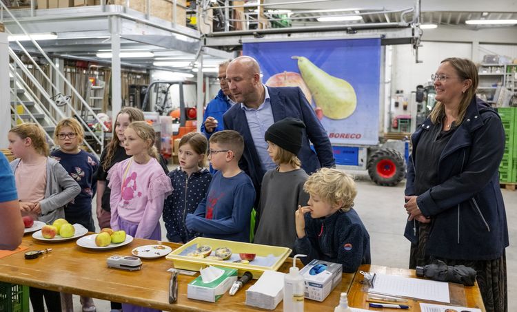 Hessens Landwirtschafts- und Umweltminister Ingmar Jung beim 8. Tag der Nachhaltigkeit. Er steht mit mehreren Kindern vor einem Tisch. Auf dem Tisch liegen Äpfel auf verschiedenen Tellern. Mit den Äpfeln werden verschiedene Experimente durchgeführt.