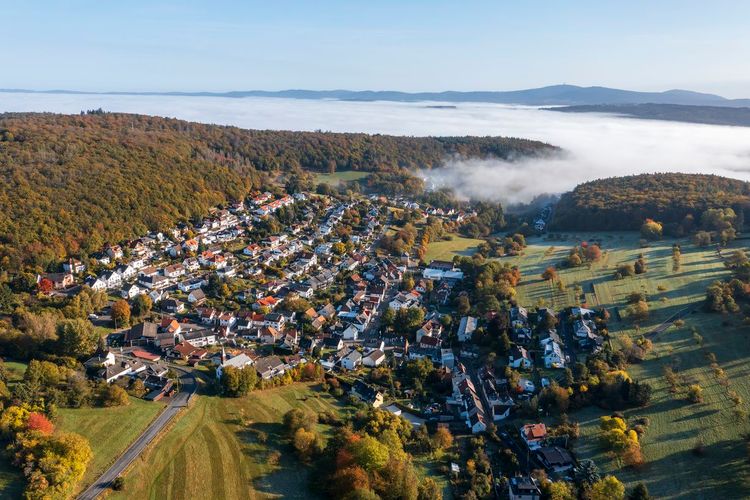 Luftaufnahme eines kleinen Dorfes im Taunus mit Morgennebel über dem Tal